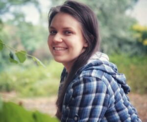 Portret uśmiechniętej autorki w otoczeniu zieleni